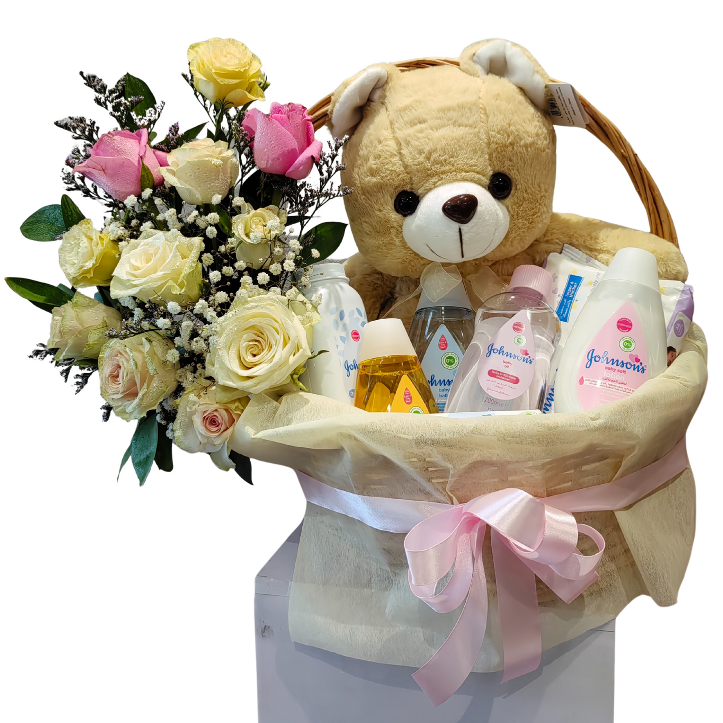 Baby essentials gift basket with plush teddy bear, Johnson’s baby care products, pink and ivory rose bouquet, and pink ribbon– perfect newborn gift from Hayat Flowers Dubai.