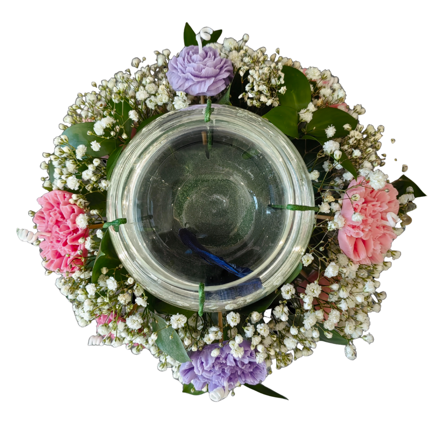 Clear glass candle holder surrounded by a beautiful arrangement of fresh, white gypsophila and ruscus leaves, and accented with pink and purple carnation-shaped flower candles.