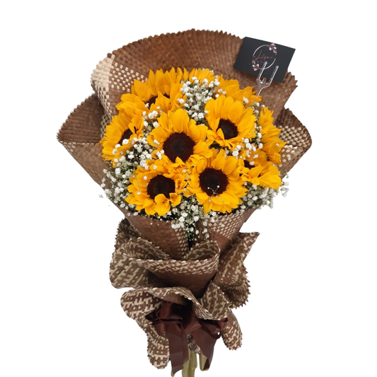 Bouquet of sunflowers and white gypsophila wrapped in handwoven Filipino bariw mat with rustic twine, ideal for eco-friendly gifting and home décor.