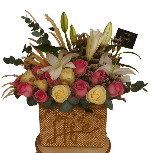 Ethereal Blush floral arrangement with pink and white roses, lilies, limoniums, eucalyptus, and pampas grass in a handwoven buri bag. Solid white background