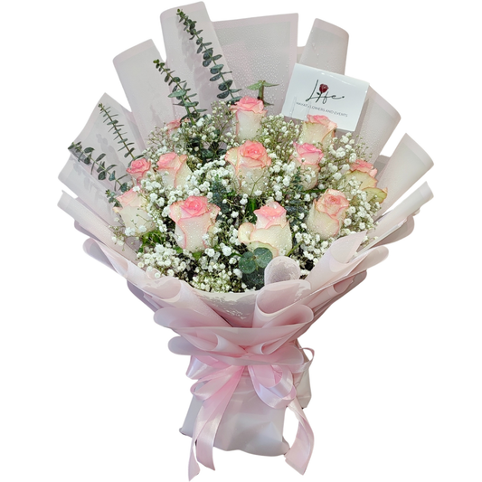 Bouquet of 12 blush-tipped roses with baby’s breath and eucalyptus, wrapped in pastel pink with a satin ribbon-– Rosé Blush by Hayat Flowers.