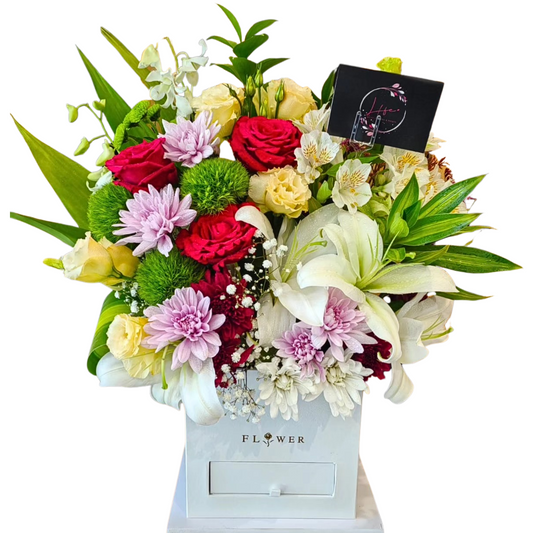 A vibrant bouquet of tropical flowers in a white floral box.