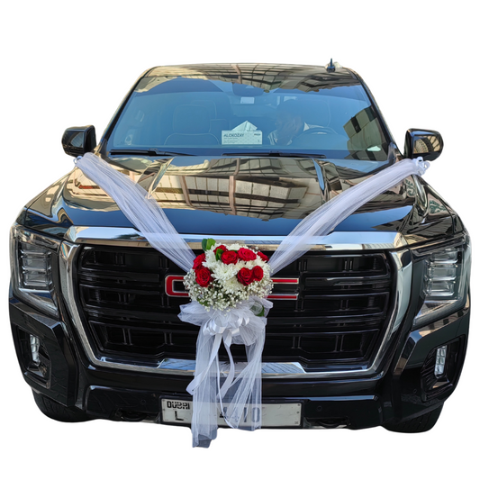 PURE LOVE bouquet tied with white chiffon fabric and satin ribbon gracing on a black GMC Yukon SUV wedding car by Hayat Flowers and Events.