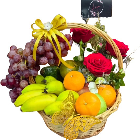 Colorful fruit basket filled with grapes, bananas, oranges, avocados, and fresh red roses.