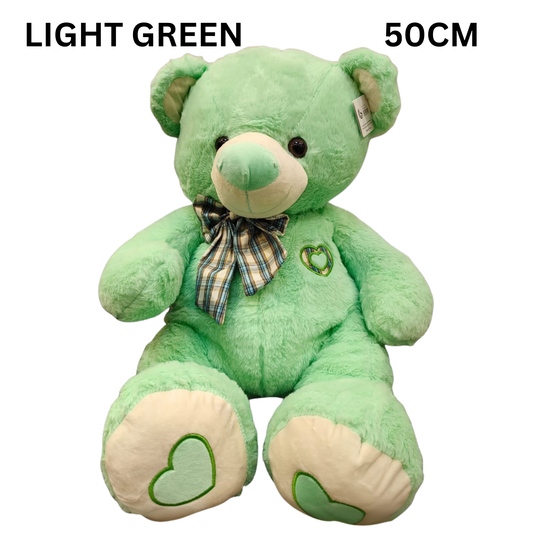 Light green teddy bear with a plaid bow tie.